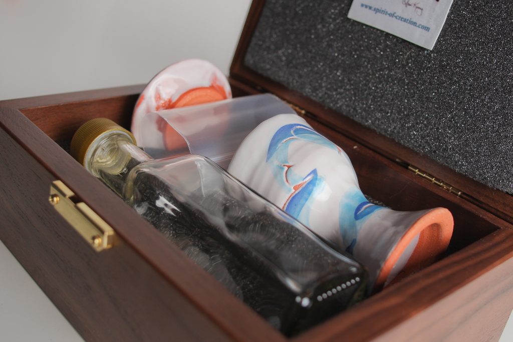 Walnut box (made in USA), custom made to fit the set, with hard foam on the inside bottom of the box, which is carved to hold the set. Soft foam lines the lid to cushion the ceramics for travel.